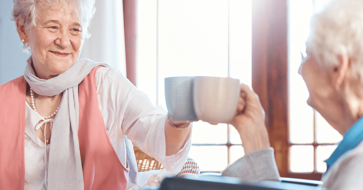 Two elder women clinking coffee mugs finding connection and purpose during retirement in Ashland.